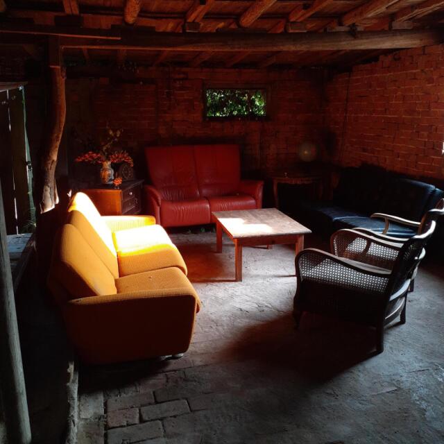 A living room situation in a former pigsty ... various chairs and sofas around a low table, sunlight breaking in from the right