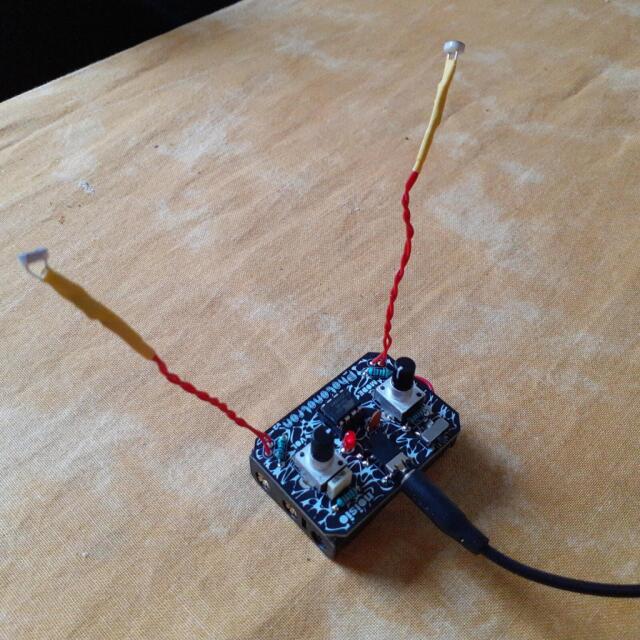 A small DIY board on a table, the two light sensors controlling this mini synth extended on wires, standing above like deep ocean fish eyes. A small DIY board on a table, the two light sensors controlling this mini synth extended on wires, standing above like deep ocean fish eyes.