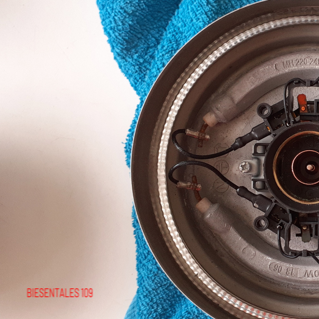 Half of an underside of an electric water kettle, on a turqouise towel, on a white table surface. Half of an underside of an electric water kettle, on a turqouise towel, on a white table surface.